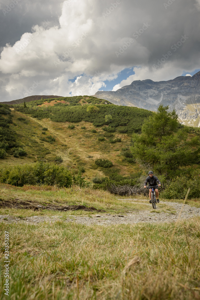 Biker in the mountain, Mountain biker on the mountain pasture with mountains and blue sky as a background, traveling alone, on the corona time,