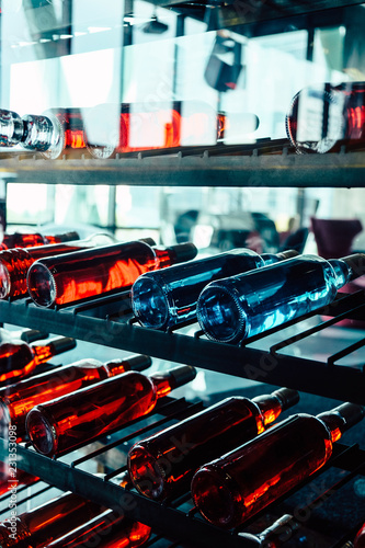 Rows of colourful wine bottles, Detail image of Metal rack with plenty of wine bottles composed in rows for decor.