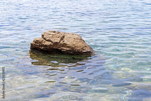 Solitary rock boulder in the sea water horizontal right