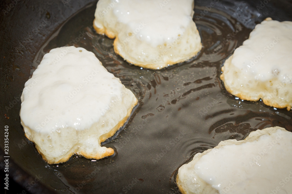 Cooking pancakes on a black pan with oil