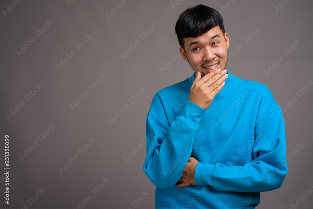 Fototapeta premium Portrait of young Asian man against gray background