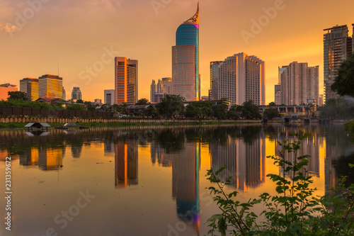 The evening sun shines on office buildings in Jakarta, Indonesia. Business center buildings reflected in the water.