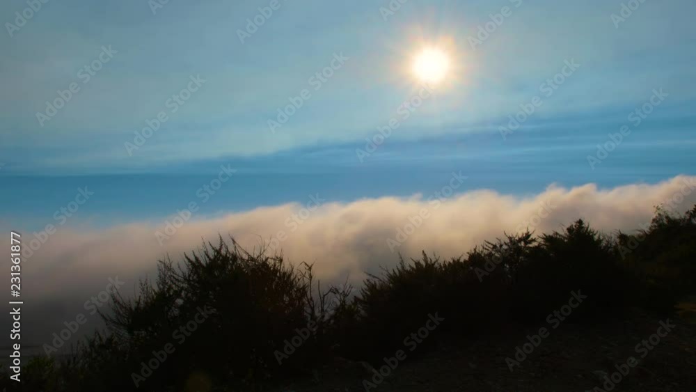 The sun shines above a billowing evening cloud layer in Big Sur California The sun shines above a billowing evening cloud layer in Big Sur California