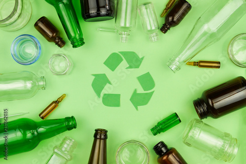 Green recycle sign symbol with glass trash garbage bottle, pills and tubes on green isolated background. Ecology recycle, environment issue, safe planet, refuse reuse recycle concept