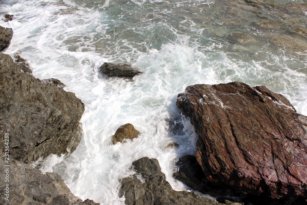 Sea water coastline with rocks, boulders and breaking waves
