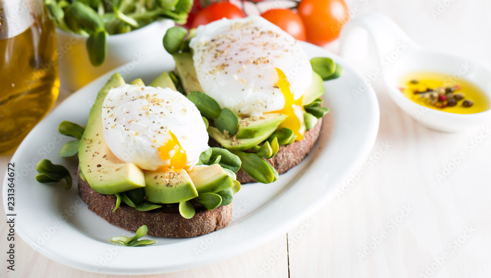 Avocado toast, cherry tomato on wooden background. Breakfast with toast avocado, vegetarian food, healthy diet concept. Healthy sandwich with avocado and poached eggs. Avocado toast, cherry tomato on wooden background. Breakfast with toast avocado, vegetarian food, healthy diet concept. Healthy sandwich with avocado and poached eggs.