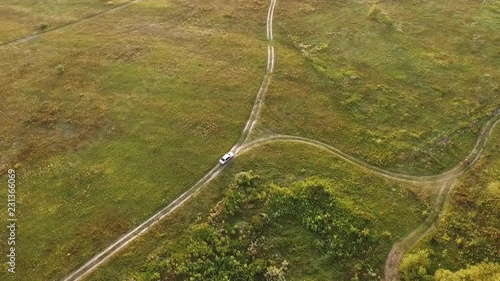 White car on scenic unpaved road with fork aerial tracking shot on sunset