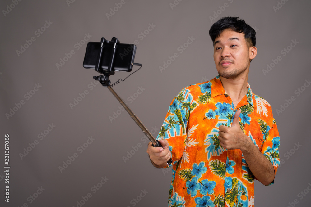Young Asian tourist man ready for vacation against gray backgrou Young Asian tourist man ready for vacation against gray backgrou