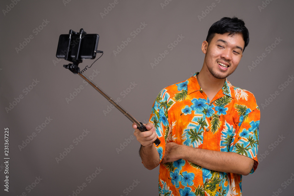 Young Asian tourist man ready for vacation against gray backgrou
