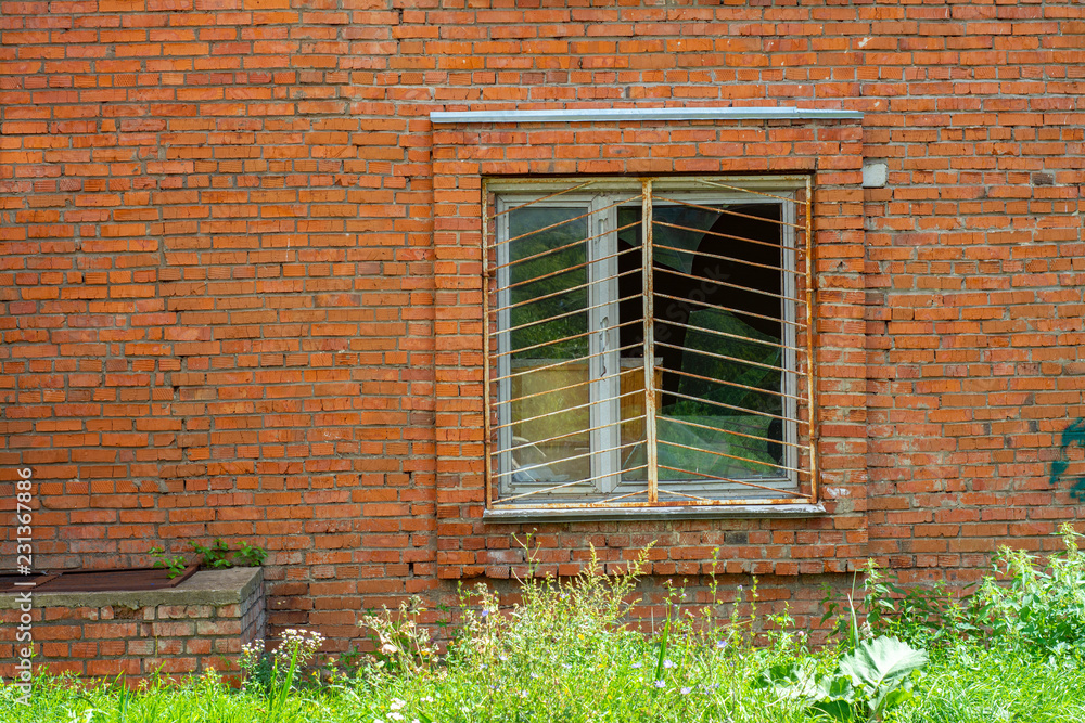 The barred window in the brick wall of the house
