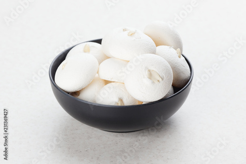 White Meringue on a black plate. Smooth meringues with peanuts.