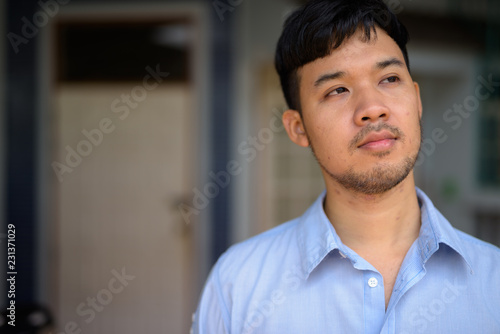 Young Asian businessman thinking at home outdoors