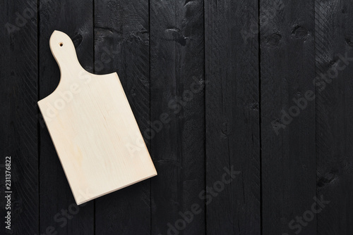 Top view of empty chopping board on black wooden table with copy space.