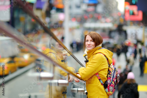 Happy young woman tourist sightseeing at Times Square in New York City. Female traveler enjoying view of downtown Manhattan.