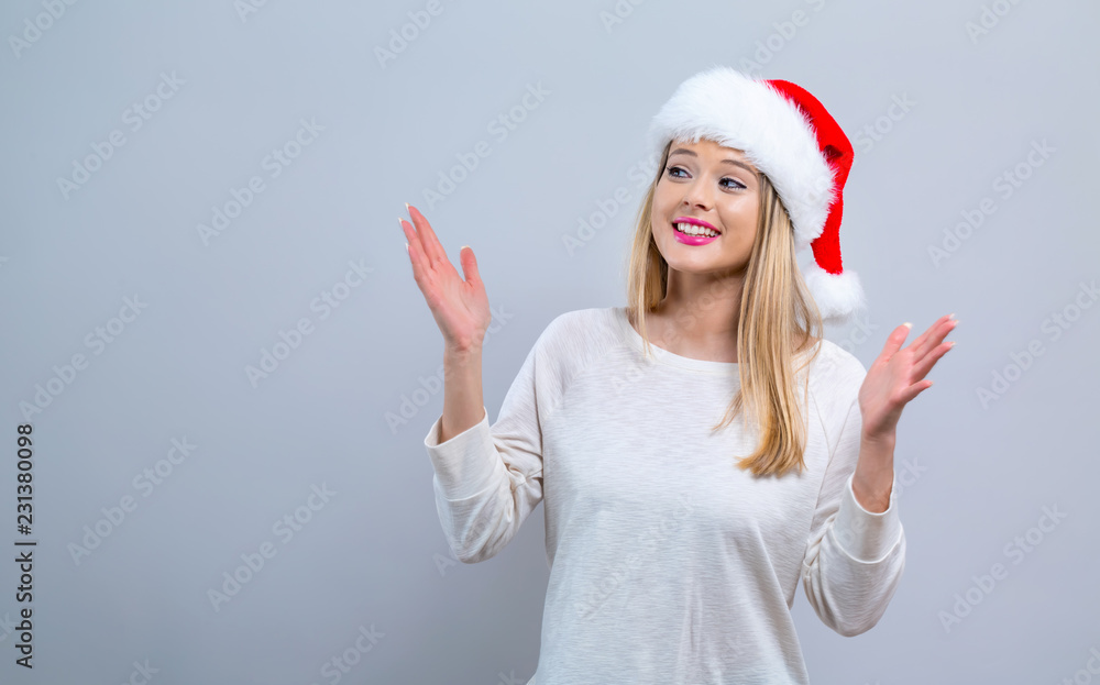 Happy woman with a Santa hat on a gray background Happy woman with a Santa hat on a gray background