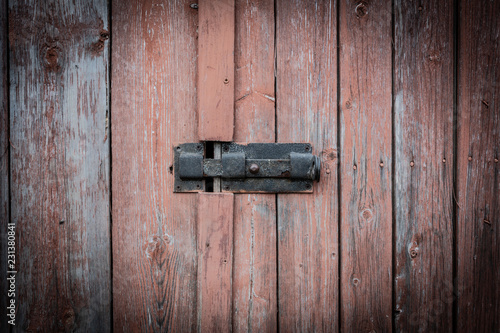 The red wooden door of an old house with a lock and bolt. Door bolt photos.