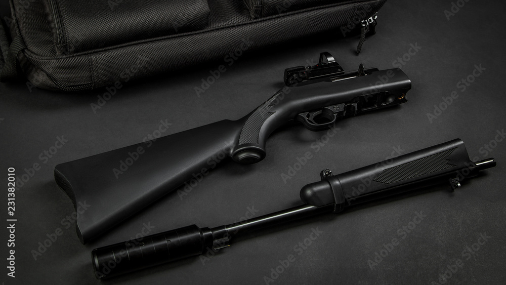 disassembled black rifle 22lr with a collimator sight and a silencer on a black disassembled black rifle 22lr with a collimator sight and a silencer on a black