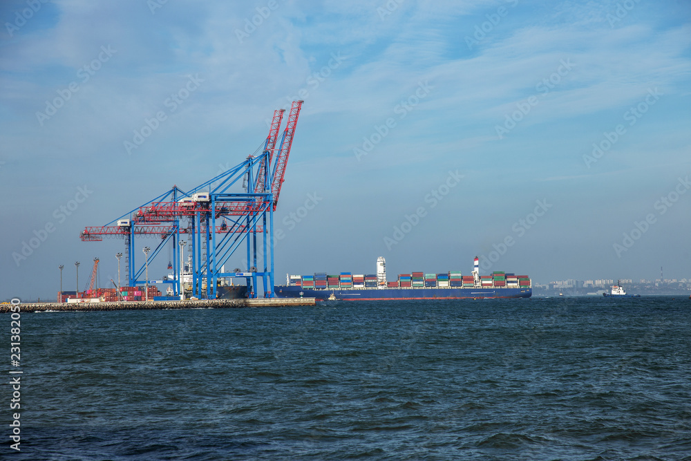 A large cargo ship enters an industrial cargo port with bridges of port marine cranes. Container ship, cargo ship, sea vessel in the sea fairway of the cargo port Odessa