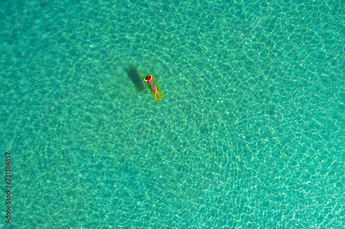 Aerial view of slim woman swimming on the swim mattress in the transparent turquoise sea in Seychelles. Summer seascape with girl, beautiful waves, colorful water. Top view from drone © gawriloff