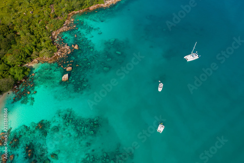 Spectacular aerial view of some yachts and small boats floating on a clear and turquoise sea, Seychelles in the Indian Ocean.Top view from drone