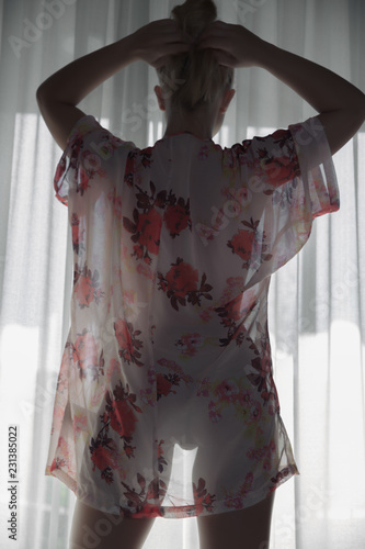 Woman standing at the window in see trough kimono without her pants