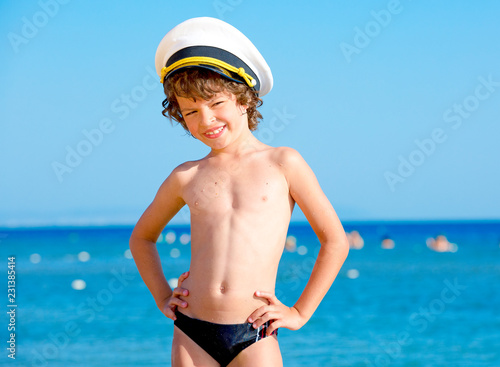 Funny child in a sea cap looking at the camera on the background of blue sea and sky © kravik93