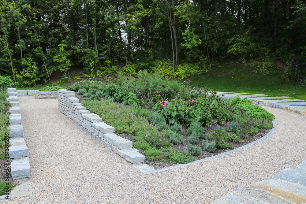 Moderner Garten- und Landschaftsbau: Gehwege, Platten und Mauern aus Natursteinen mit Anpflanzungen