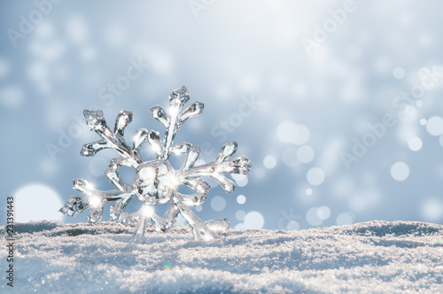 Leuchtender großer Eiskristall im Schnee, Bokeh des Winters leuchtet im Hintergrund photo