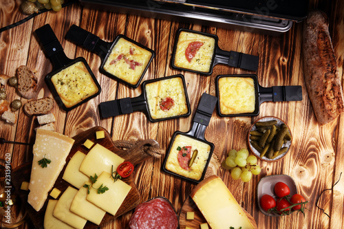 Photography Delicious traditional Swiss melted raclette cheese served in individual skillets with salami