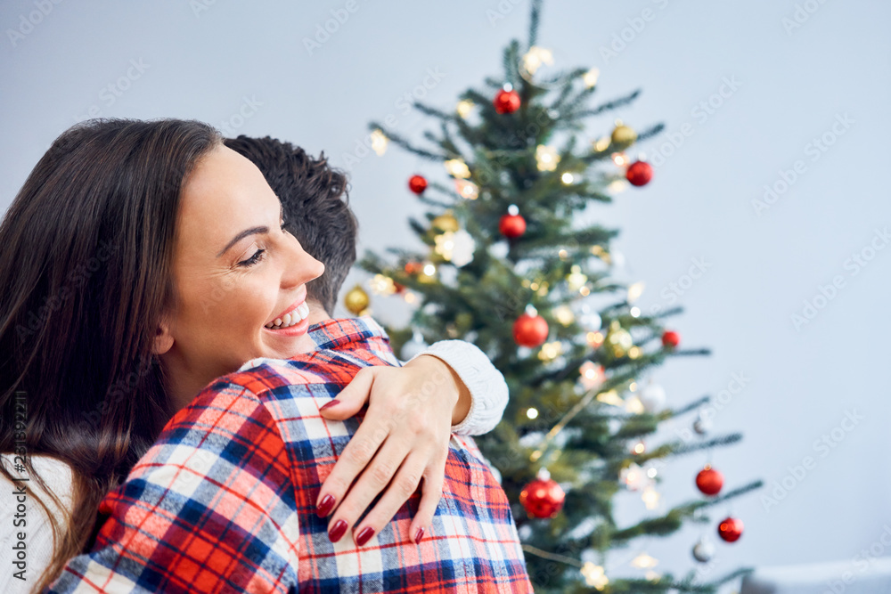 Portrait of happy couple embracing during christmas celebration with decorations in background Portrait of happy couple embracing during christmas celebration with decorations in background