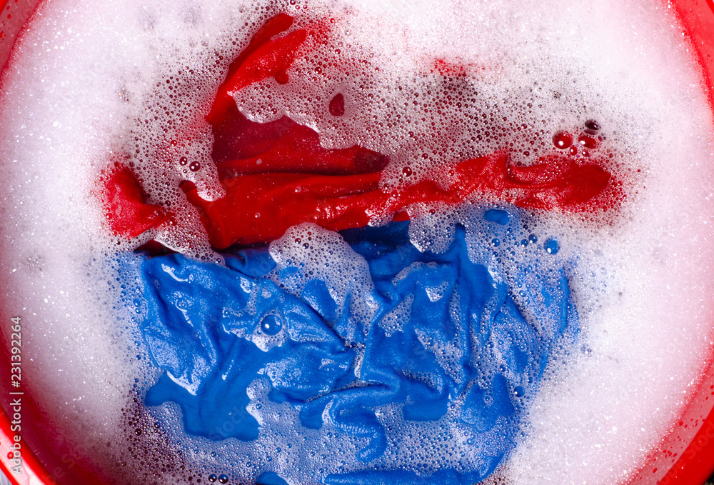 Fototapeta premium Washing color clothes in basin enemale powdered detergent, top view