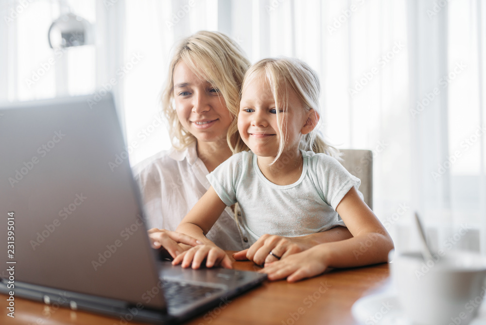 Smiling mother and child uses laptop at home Smiling mother and child uses laptop at home