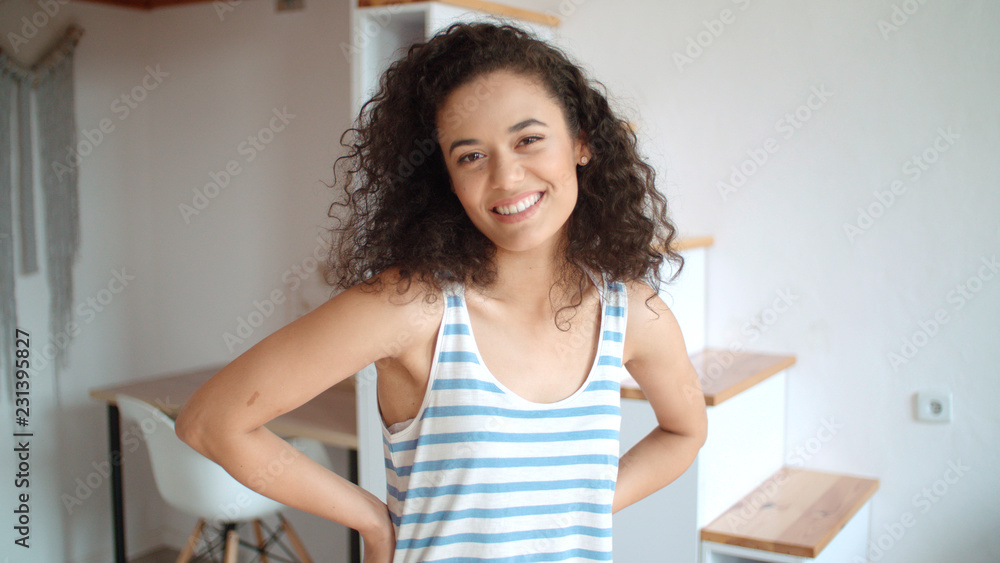 Portrait of a beautiful young woman smiling at the camera in a kitchen.