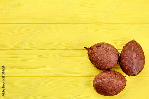 Three whole coconuts and copy space. Brown coconuts on yellow wooden surface. Health benefits of coconuts.
