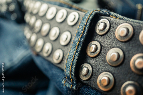 close up detail of an unbuckled leather belt on a faded pair of blue jeans