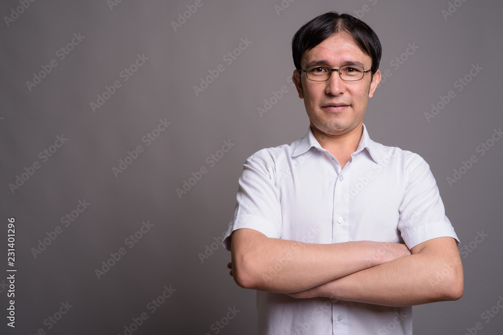 Young Asian nerd man wearing eyeglasses against gray background