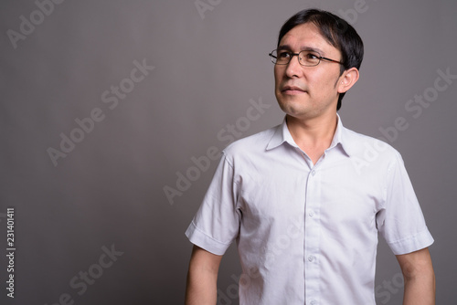 Young Asian nerd man wearing eyeglasses against gray background © Ranta Images