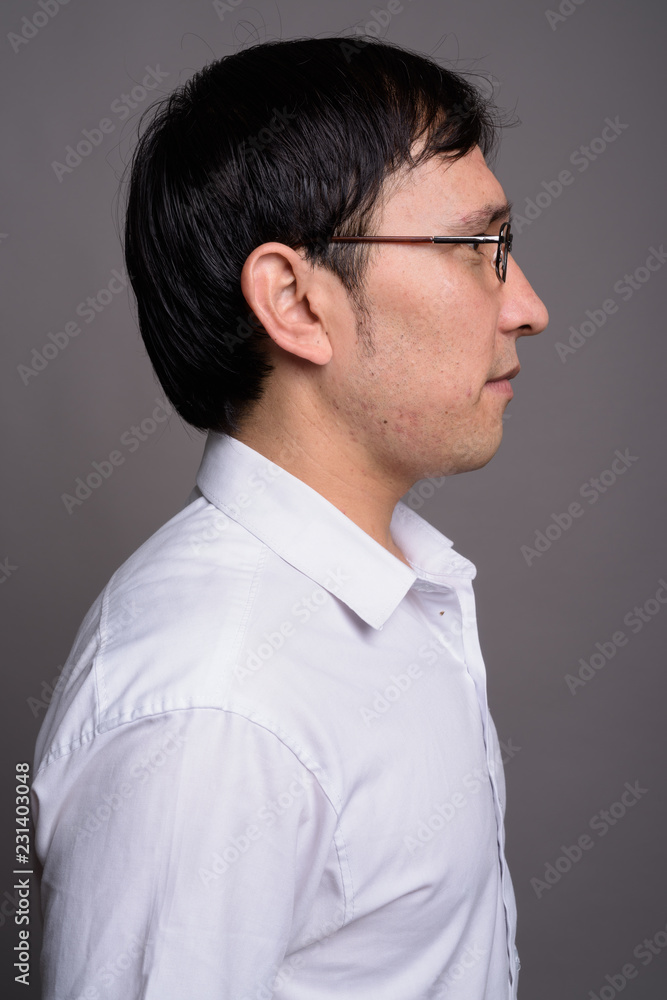 Young Asian nerd man wearing eyeglasses against gray background Young Asian nerd man wearing eyeglasses against gray background