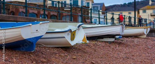 Small fishing boats lined  up on a pebble beach in Sidmouth, England