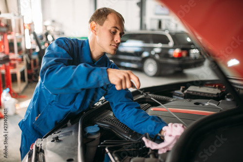 Male technician works with car engine