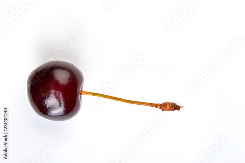 Ripe cherry with stem and copy space. Fresh juicy berry on light background.