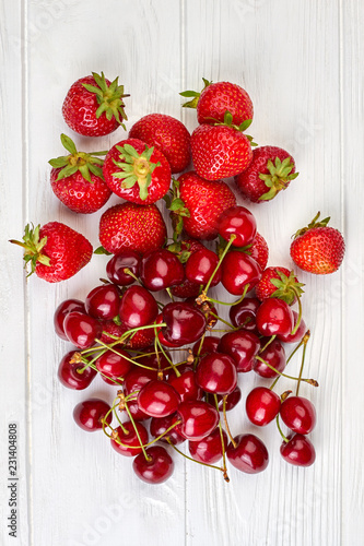 Red natural berries, top view. Ripe fresh cherries and strawberries on white wooden background. Fresh from garden.