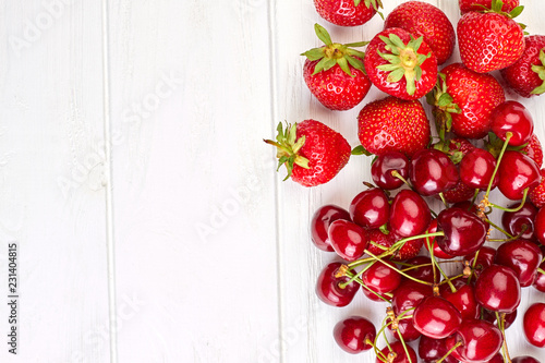 Fresh ripe berries and copy space. Side border from red organic strawberries and cherries on white surface with text space.