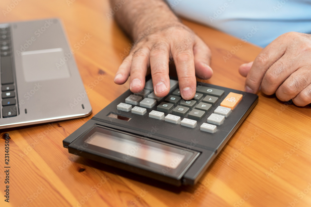Man using calculator, calculating bills at home.