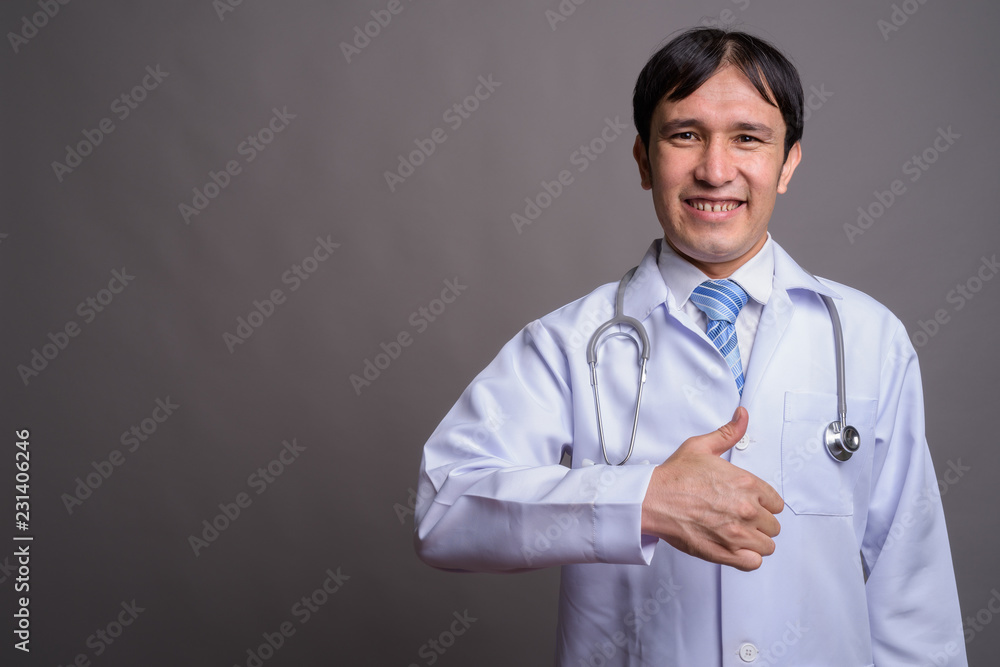 Young Asian man doctor against gray background Young Asian man doctor against gray background