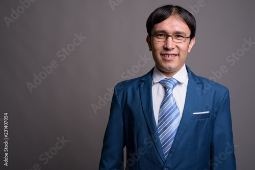 Portrait of young Asian businessman against gray background