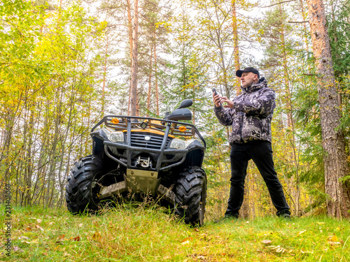 A man chooses a route on the navigator. ATV. Journey through the forest. Off-road. The driver checks the route on the map. Trips on ATV. Quad bike in the forest.
