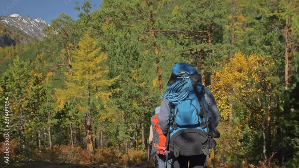 Family travels. People environment by mountains, rivers, streams. Parents and kids walk using trekking poles. Man and woman have professional hiking backpacks, flasks, mugs and other equipment. Dad Family travels. People environment by mountains, rivers, streams. Parents and kids walk using trekking poles. Man and woman have professional hiking backpacks, flasks, mugs and other equipment. Dad