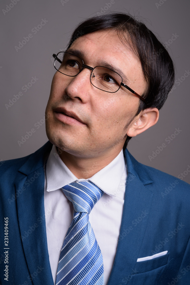 Portrait of young Asian businessman against gray background Portrait of young Asian businessman against gray background