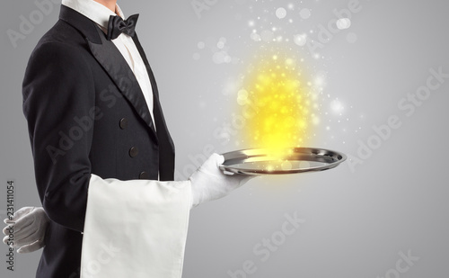 Elegant young waiter serving mysterious light on tray 
